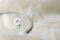 Stylish modern white round ring on mirror on soft white tulle, copy space. Unusual fused glass ring