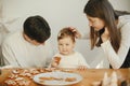 Stylish mother, father and cute little daughter making christmas gingerbread cookies in modern room. Happy family time together, Royalty Free Stock Photo