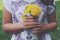 Stylish mulatto girl holding bunch of yellow dandelions