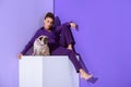 stylish mulatto girl in purple suit sitting on cube with pug dog, ultra violet Royalty Free Stock Photo