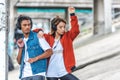 stylish multicultural couple listening music with headphones and dancing at city
