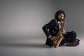 stylish musician playing saxophone while sitting