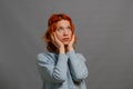 Stylish mysterious woman with red hair. Lights on the hair. Amazed look. Gray background. Side view