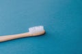 Stylish natural eco friendly toothbrush with wooden bamboo handle on blue background