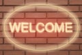 Stylish neon sign WELCOME on brick wall
