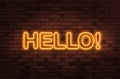 Stylish neon sign with word Hello on brick wall