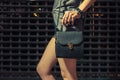 Stylish night fashion portrait of trendy casual young woman with black leather handbag posing near metallic urban wall Royalty Free Stock Photo