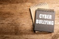 Stylish notebooks with phrase CYBER BULLYING on wooden table. Space for text