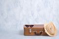 Stylish Old Fashioned Accessories Of Hipster Female Traveller: Vintage Sunglasses, Straw Hat, Leather Suitcase On Grey Background.