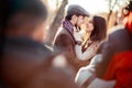 Stylish old fashioned couple among crowd looking at each other outdoors in backlight. Man wearing tweed flat cap, brown