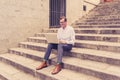 Stylish old man working on laptop surfing the internet sitting on stairs outdoors city in digital nomad Senior using modern Royalty Free Stock Photo