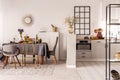 Stylish open plan kitchen and dining room interior with white cupboard and long table with grey tablecloth and food Royalty Free Stock Photo