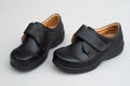 Stylish pair of black leather shoes featuring an adjustable velcro strap on a white background