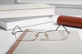 Stylish pair of glasses with metal frame on white table, closeup