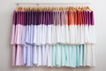 Stylish pastel colored dresses hanging on hangers evoke freshness and style against white background