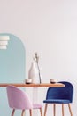 Pastel pink and petrol blue chairs at long wooden table in bright dining room Royalty Free Stock Photo