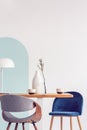 Stylish pastel pink and petrol blue chairs at long wooden table in bright dining room Royalty Free Stock Photo