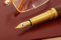 Stylish pen and glasses on a brown notepad for notes close up