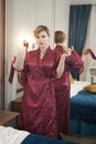 Stylish pin up short hair blonde woman with plus size curvy body posing in fashion red bathrobe near the mirror in the Royalty Free Stock Photo