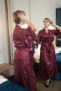 Stylish pin up short hair blonde woman with plus size curvy body posing in fashion red bathrobe near the mirror in the Royalty Free Stock Photo