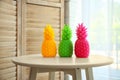 Stylish pineapple candles on table indoors