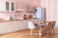 Stylish pink kitchen interior with dining table Royalty Free Stock Photo