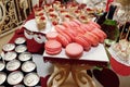 Stylish pink macaroons, candy bar with sweets at luxury wedding