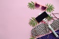 stylish pink sunglasses, modern swimsuit, phone on selfie stick, and green palm leaves on pink background, flat lay. space for t Royalty Free Stock Photo