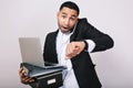 Stylish portrait busy handsome man in white shirt and black jacket holding folders, laptop, talking on phone on white