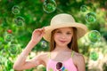 Stylish portrait of smiling girl in hat front of soap bubbles and green background. Summer season Royalty Free Stock Photo