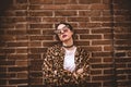 Stylish portrait of young serious woman with crossed arms wearing trendy leopartd print faux fur coat, fashion sunglasses, posing Royalty Free Stock Photo