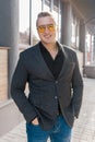 Stylish positive young attractive guy of European appearance businessman portrait in jacket, shirt and jeans, in sunglasses on the Royalty Free Stock Photo