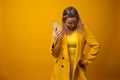 Stylish positive young woman on yellow background, copy space.