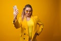 Stylish positive young woman on yellow background, copy space.