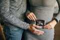 Stylish pregnant couple holding ultrasound scan of baby on baby bump. Healthy young parents holding in hands on belly photo of