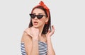 Stylish pretty young woman feeling surprised, wearing retro outfit posing over white wall. Beautiful amazed female looking through Royalty Free Stock Photo