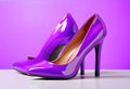 Stylish purple high heels on color background