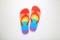 Stylish rainbow flip flops on white background, top view