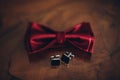 stylish red bow tie and cuff links on wooden table, groom getting ready in morning before wedding. gentleman set. Royalty Free Stock Photo