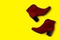 Stylish red female boots on yellow background. Space for text