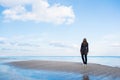 Stylish red-haired woman in dark coat and sunglasses standing on seaside with beautiful sky and water on background Royalty Free Stock Photo