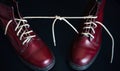 Stylish red shoes with laces linked together on black background. High boots with shoelaces connected together, close-up. Concept