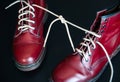 Stylish red shoes with laces linked together on black background. High boots with shoelaces connected together, close-up. Concept Royalty Free Stock Photo