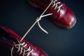 Stylish red shoes with laces linked together on black background. High boots with shoelaces connected together, close-up. Concept Royalty Free Stock Photo