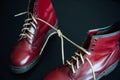 Stylish red shoes with laces linked together on black background. High boots with shoelaces connected together, close-up. Concept Royalty Free Stock Photo