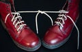 Stylish red shoes with laces linked together on black background. High boots with shoelaces connected together, close-up. Concept