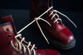 Stylish red shoes with laces tied together on black background, selective focus. High boots with shoelaces connected together,