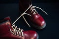 Stylish red shoes with laces tied together on black background, selective focus. High boots with shoelaces connected together,