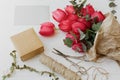 Stylish red tulips bouquet with greeting card, gift, scissors and twine on rustic white wood Royalty Free Stock Photo