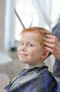 Stylish redhead boy at the barbershop. Boy 4 years old in the barbershop looks at the camera and smiles